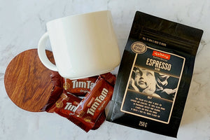 Bold Coffee Lover's Gift: A perfect package for coffee enthusiasts. Includes a 440ml Maxwell Williams white mug, 250g Yahava Koffee Works Espresso Whole Beans, three single-serve Tim Tams, and a wooden drink coaster. Ideal for espresso and stovetop brewing.
