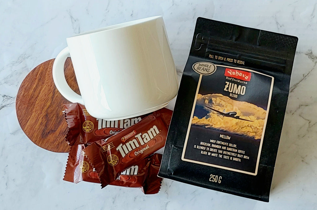 Mellow Coffee Enthusiast Gift: Includes a 440ml Maxwell Williams white mug, 250g Yahava Koffee Works Zumo Whole Beans (a smooth blend of Brazilian, Rwandan, and Sumatran coffees), three single-serve Tim Tams, and a wooden drink coaster. Perfect for a silky, flavorful coffee experience.