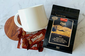 Mellow Coffee Enthusiast Gift: Includes a 440ml Maxwell Williams white mug, 250g Yahava Koffee Works Zumo Whole Beans (a smooth blend of Brazilian, Rwandan, and Sumatran coffees), three single-serve Tim Tams, and a wooden drink coaster. Perfect for a silky, flavorful coffee experience.
